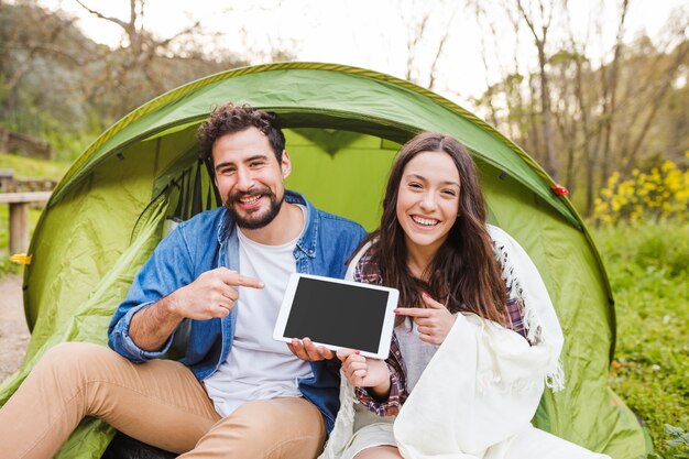 Young couple pointing at tablet in nature