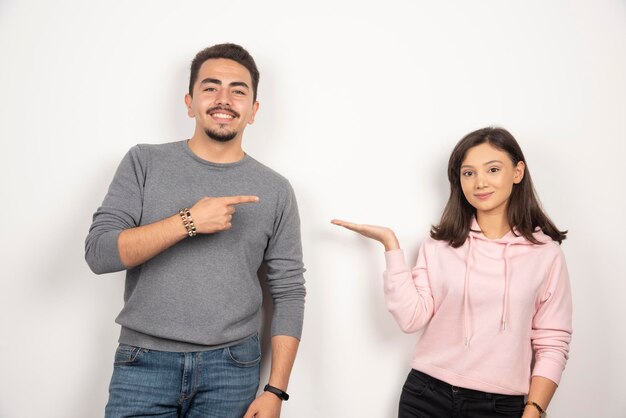 Young couple pointing at themselves on white.