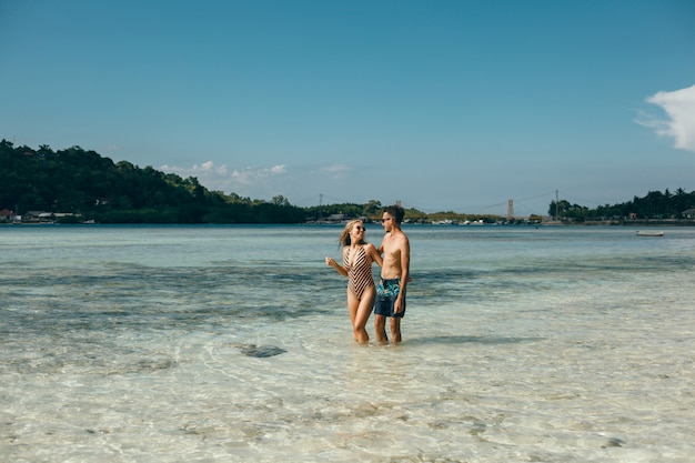 若いカップル、ビーチでポーズを取って、海で楽しく、笑って、笑って