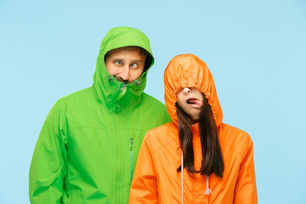 Free photo the young couple posing at studio in autumn jacket isolated on blue.