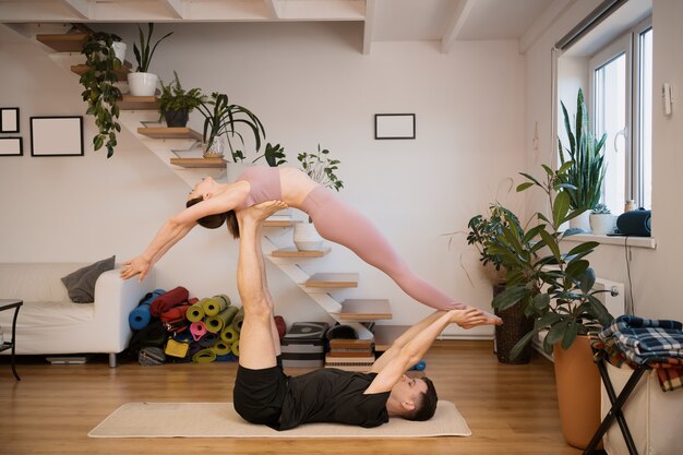 Young couple practicing acro yoga together at home in a modern interior. Hobby, togetherness, healthy lifestyle