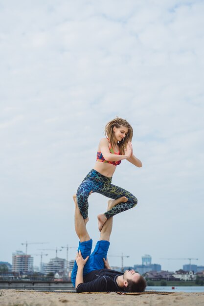 young couple practicing yoga on city background