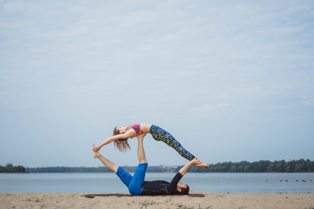 young couple practicing yoga on city background