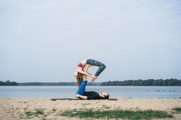young couple practicing yoga on city background