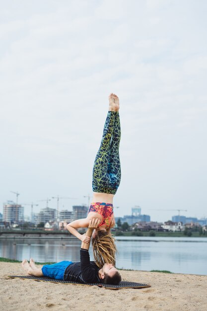 young couple practicing yoga on city background