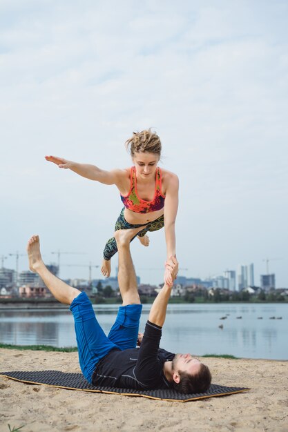 young couple practicing yoga on city background