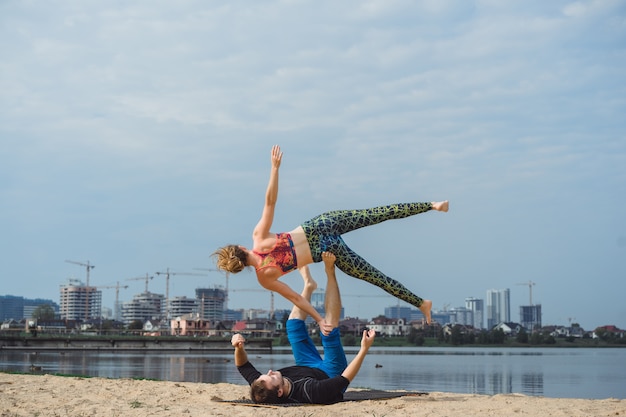 young couple practicing yoga on city background