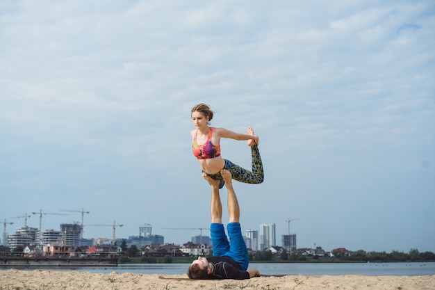 young couple practicing yoga on city background