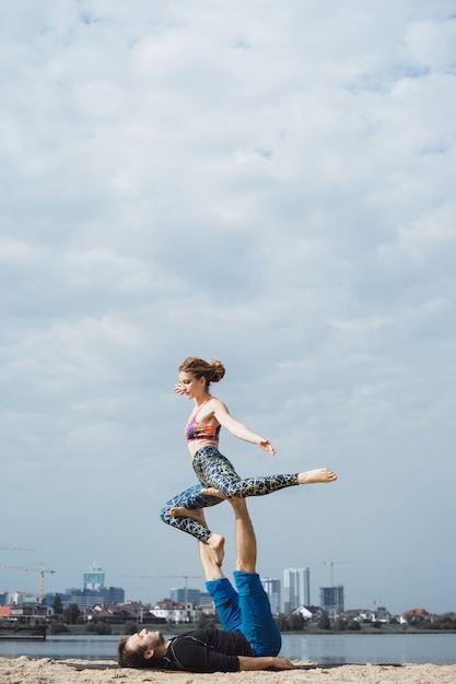 young couple practicing yoga on city background