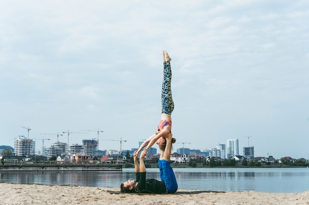 Бесплатное фото Молодая пара, практикующих йогу на фоне города