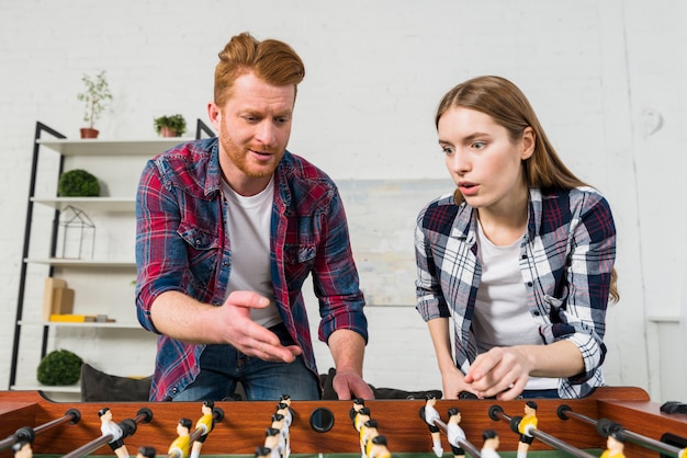 Young couple quarreling while playing the table soccer game