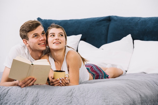 Young couple reading book on bed