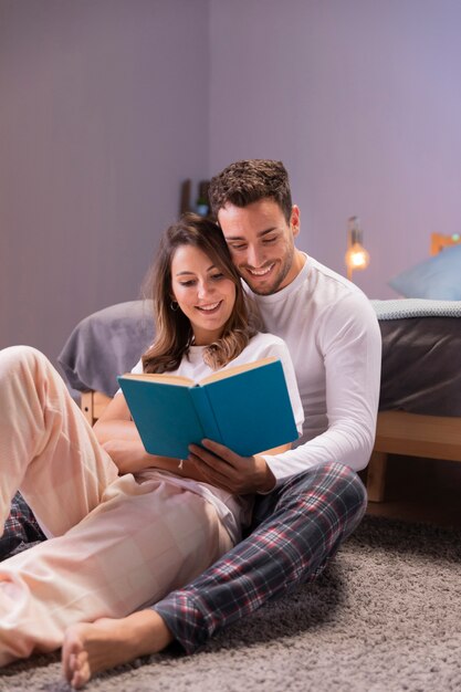 若いカップルがベッドで一緒に読んで