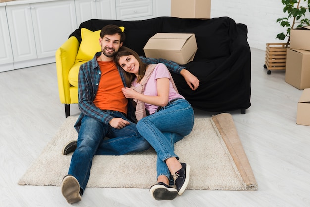 Young couple relaxing on carpet near the sofa of new house