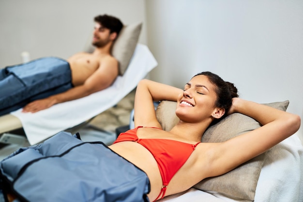 Молодая пара отдыхает во время прессотерапии в спа-салоне В центре внимания счастливая женщина