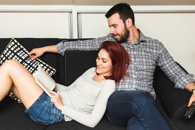 Young couple relaxing on sofa reading book