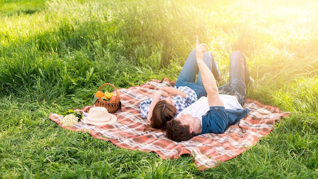 Foto gratuita giovani coppie che riposano sulla coperta nella foresta