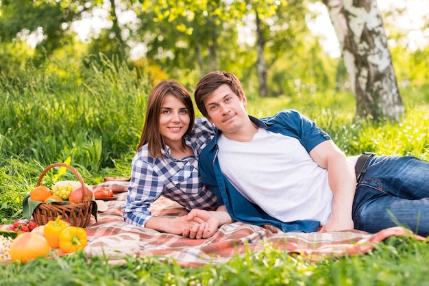 Free photo young couple resting on blanket and holding hands