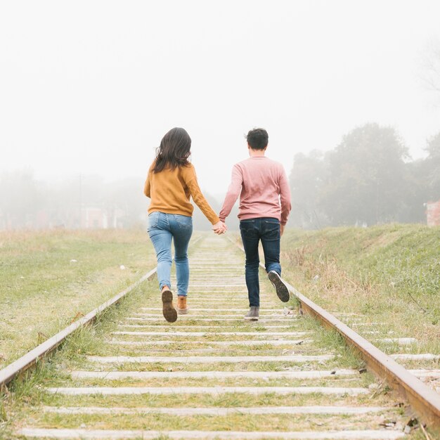 Young couple running along tracks