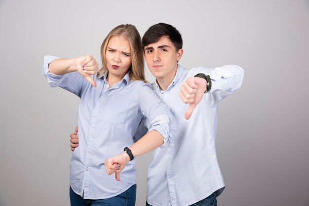 Young couple showing thumb down with negative expression.