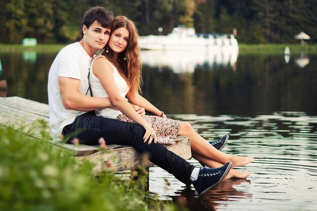 池のそばに座っ若いカップル
