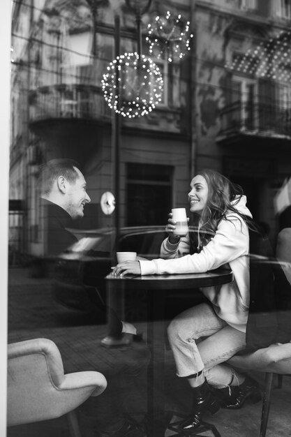 Young couple sitting in a cafe behind the window