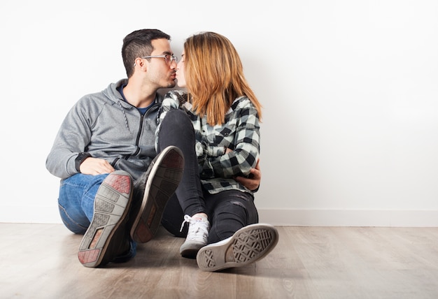 Young couple sitting on the floor kissing