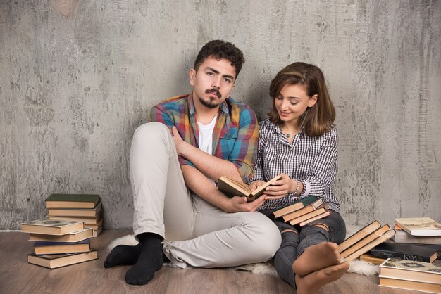 young couple sitting on the floor and reading a book