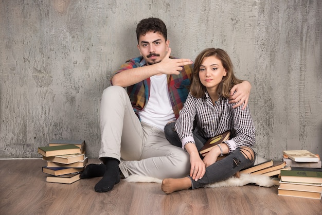 молодая пара сидит на полу с книгами