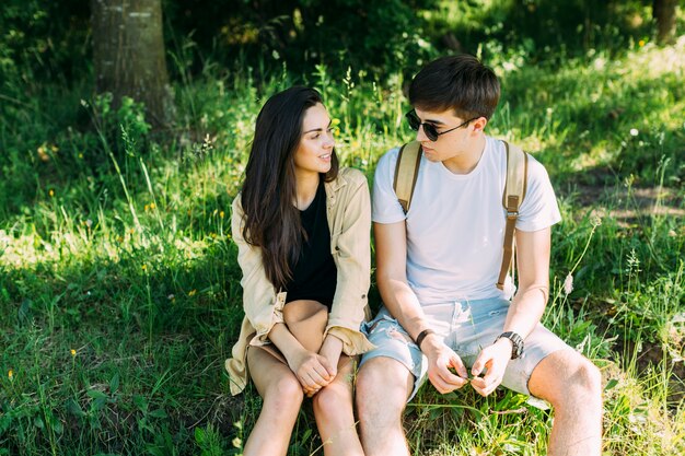 Young couple sitting on green grass looking at each other