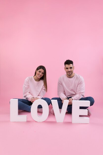 Young couple sitting near big love sign