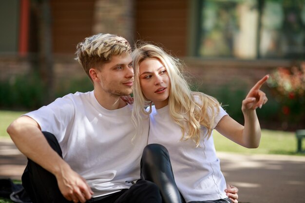 Молодая пара сидит в парке и смотрит в сторону Фото высокого качества