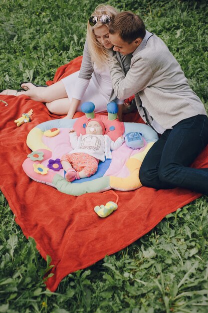 Young couple sitting on a red blanket with their baby