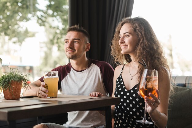 Young couple sitting in restaurant holding drinks