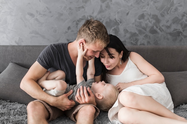 young couple sitting on sofa loving their son