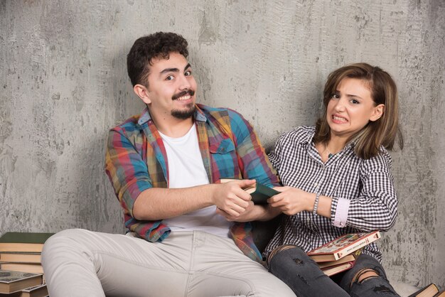 young couple sitting and taking a book from each other