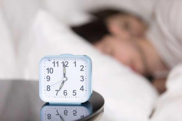 Free photo young couple sleeping in bed next to an alarm clock