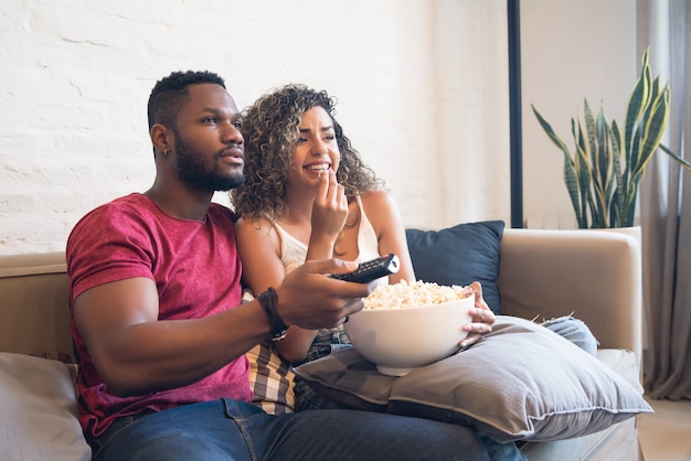 젊은 부부는 함께 시간을 보내고 집에서 소파에 앉아 TV 시리즈나 영화를 봅니다.