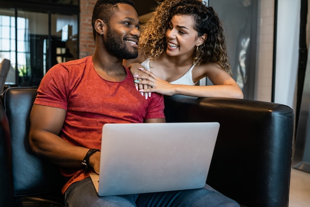 Young couple spending time together while using a laptop at home. New normal lifestyle concept.