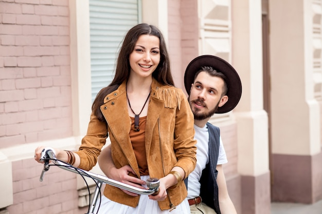 Free photo young couple standing against the wall and hugging