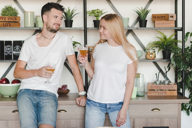 Young couple standing in front of shelf holding glasses of beer