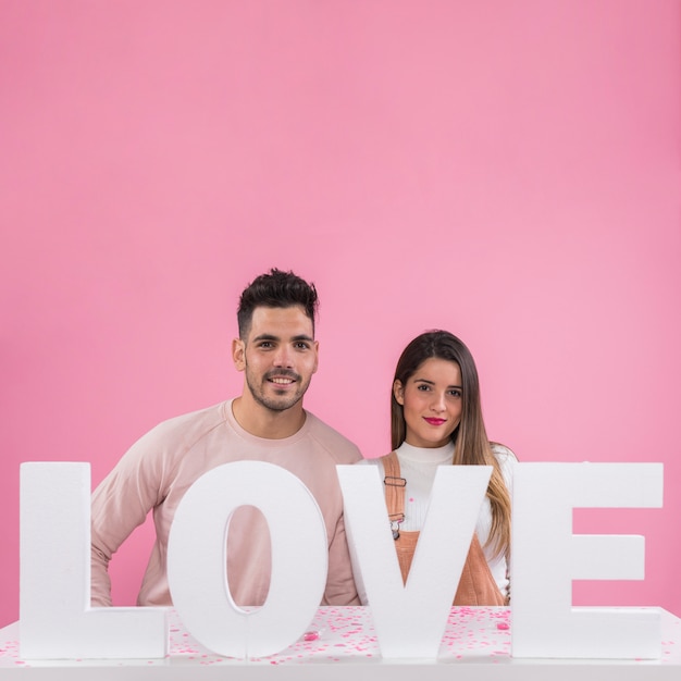 Young couple standing near Love inscription 