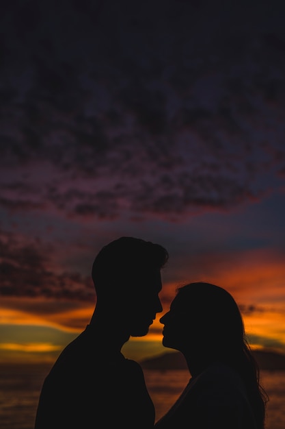 Young couple standing on sea shore in evening