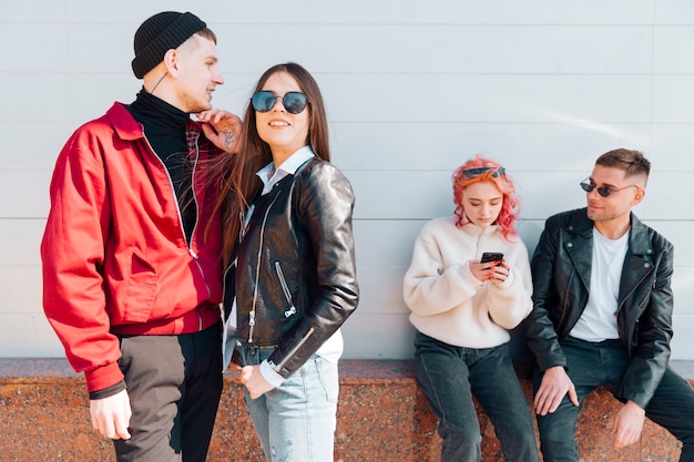 Young couple standing while other pair looking in smartphone 