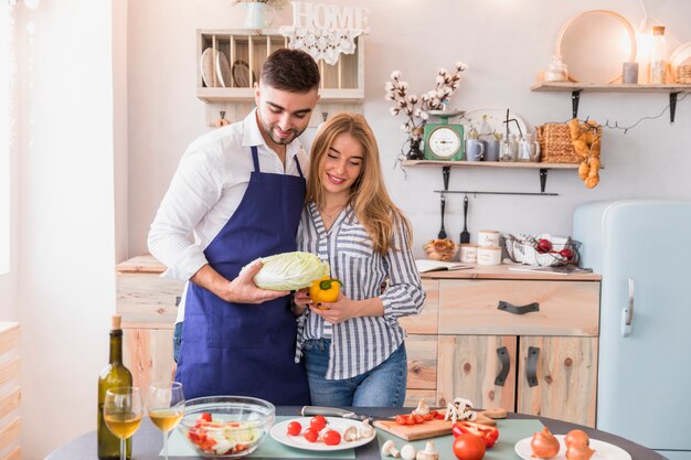 Young couple standing with vegetables at table