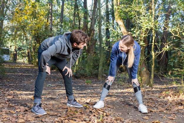 Young couple stretching muscles before jogging in nature