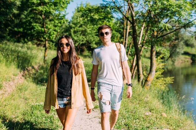 Young couple in sunglasses walking near lake