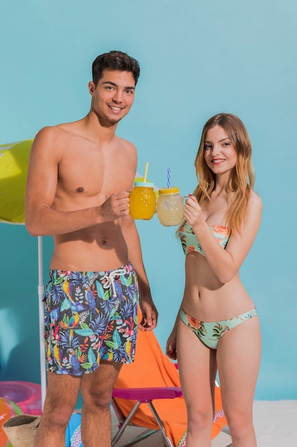 Young couple in swimwear clinking cocktail glasses 