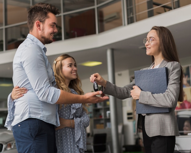 Young couple taking keys from a  car dealer