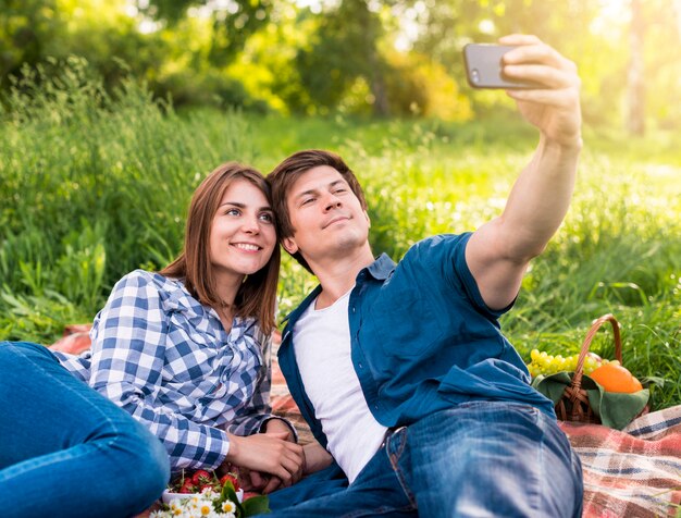 Young couple taking selfie on plaid outside